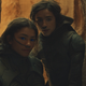 Zendaya's Chani and Timothée Chalamet's Paul huddle close together between rock formations in Dune.